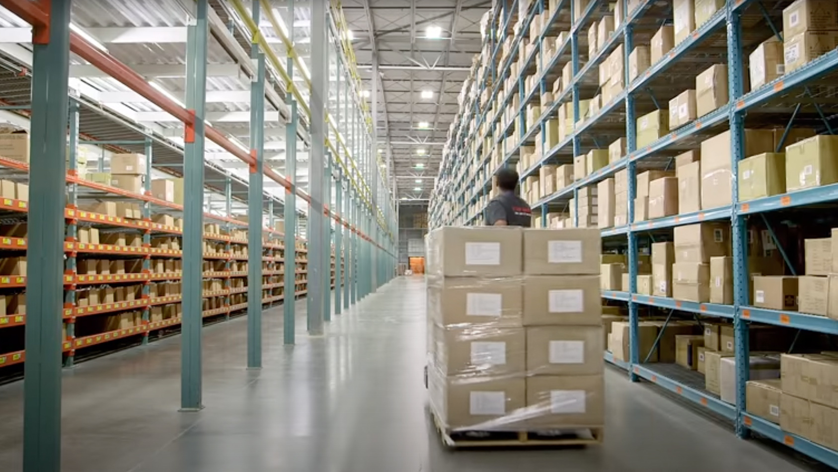 photo of warehouse worker moving a pallet of boxes